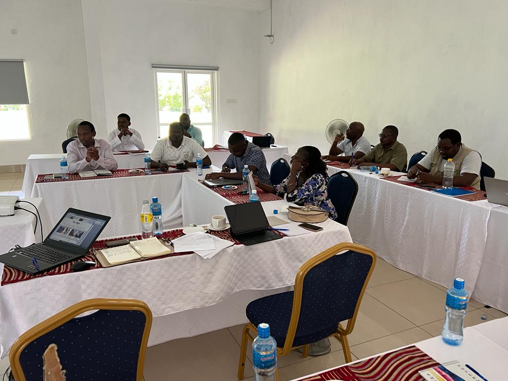 Participants seated around a U-shaped conference table with laptops and papers during a consultative meeting