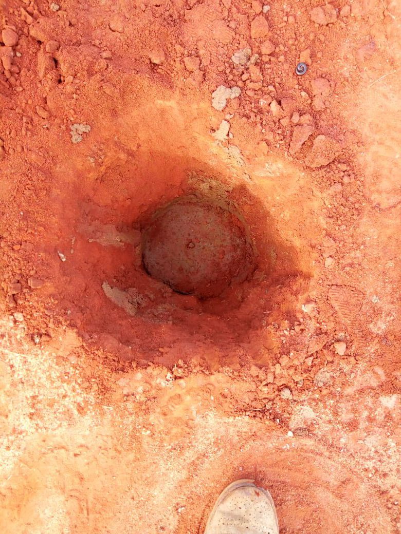 Close-up of a survey control point set in a hole in red soil