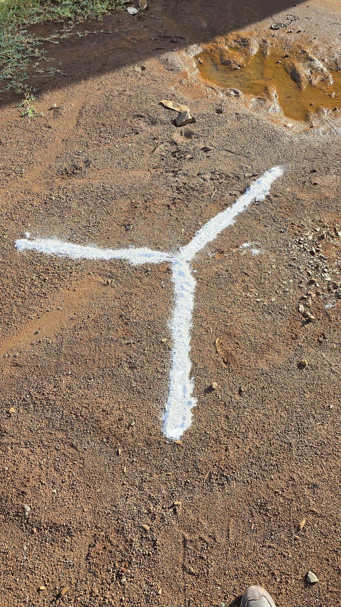 A ground control point marked on gravel with a white painted Y-shaped target