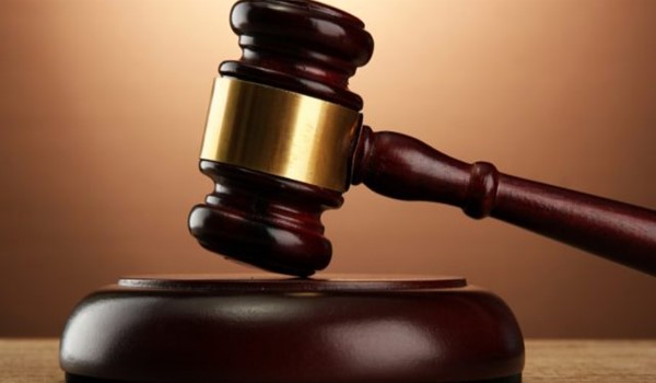 A wooden judge’s gavel resting on its sound block