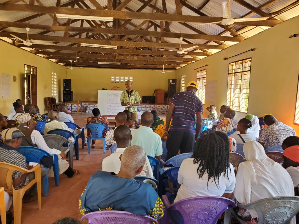 Residents seated in a large hall with a timber roof during a public participation session
