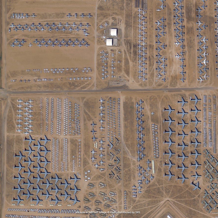 Satellite imagery of hundreds of parked aircraft in long rows on bare desert ground
