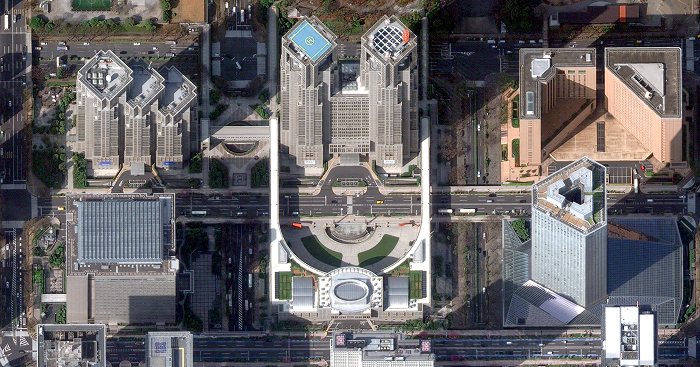 Satellite imagery looking straight down on a city centre: tower blocks with rooftop plant, a formal plaza between them and streets lined with trees