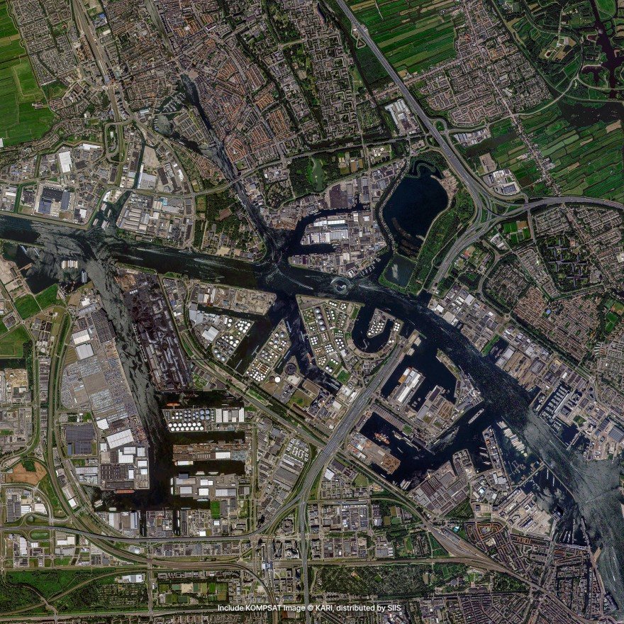 Satellite imagery of a port city: docks and basins cut into the waterfront, warehouses and industrial yards, and a motorway interchange